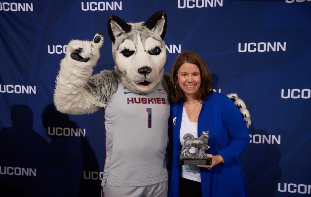 Cinnamon Adams of the Graduate School poses with Jonathan the Husky after receiving the University Citizen Award